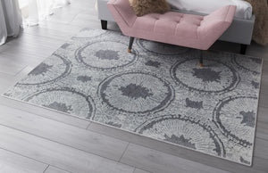 Close-up view of a Boho grey area rug with circular abstract patterns under a pink bench.