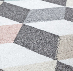 Close-up of geometric rug with 3D cube patterns in grey, pink, and blue, highlighting texture and intricate design. Perfect for modern decor.