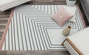 Living room with a modern rug featuring black geometric lines on a white background and a brown border, enhancing contemporary decor.