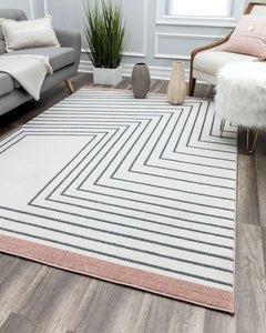 Cozy living room with a grey sofa, a white armchair, a rustic firewood holder, a blue and grey abstract rug, and decorative plants.