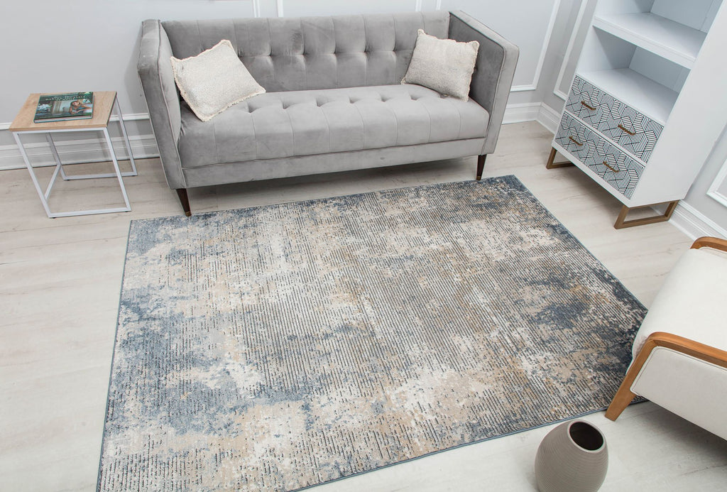 Distressed blue and beige abstract rug in a modern living room with a gray sofa and stylish decor.