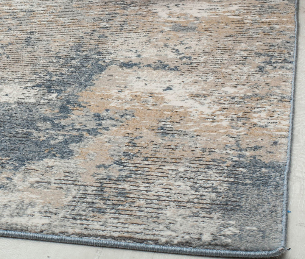 Close-up of the edge of a distressed blue and beige abstract rug, highlighting its textured and detailed design.