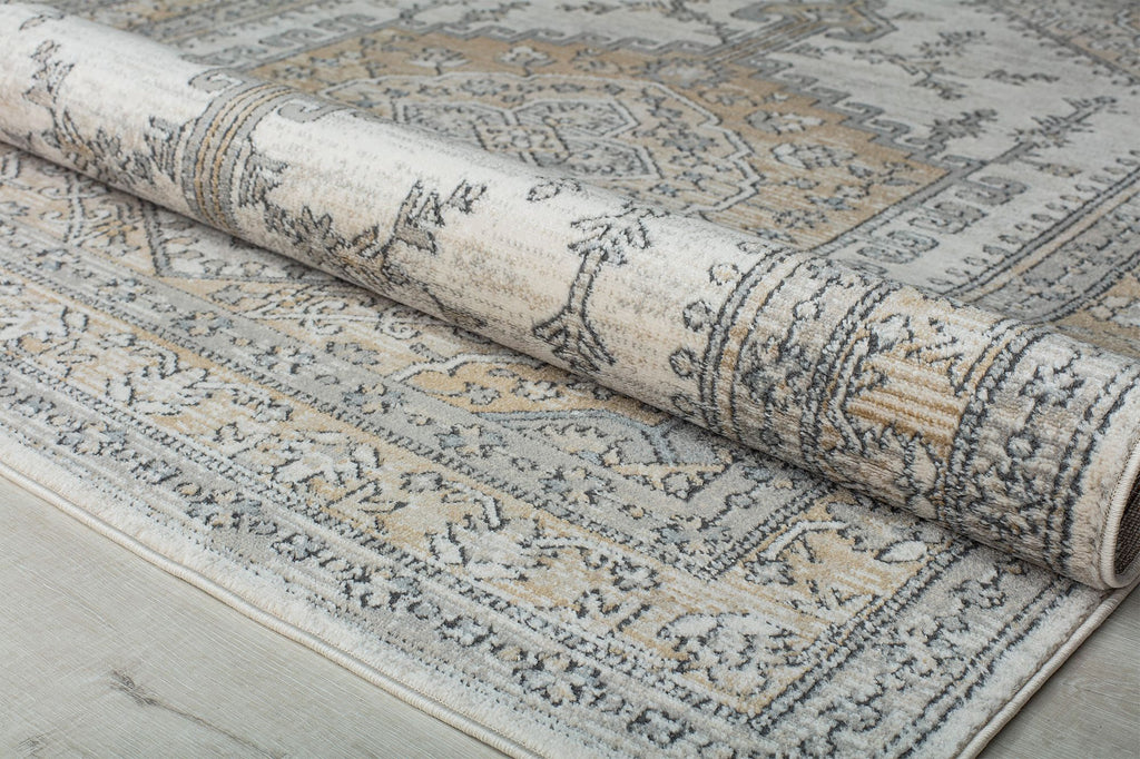 Rolled beige and gray abstract patterned rug showing intricate designs.