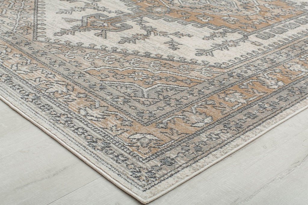 Close-up of the corner of an abstract beige and gray patterned rug.