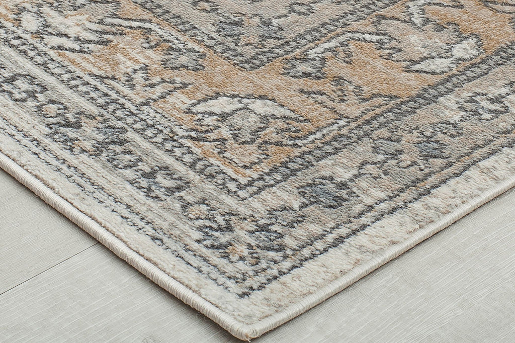 Detailed view of the corner of a beige and gray abstract rug.