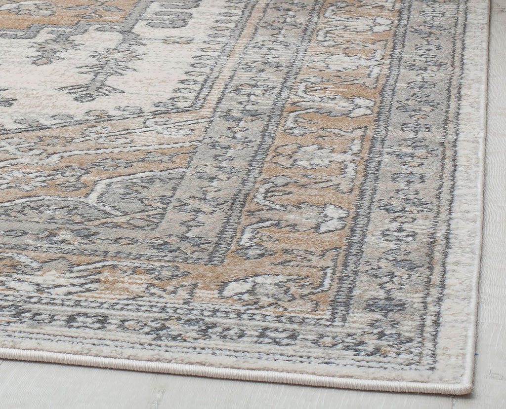 Close-up view of the border of an abstract beige and gray rug.