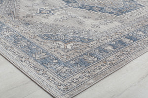 Close-up of an abstract blue and beige rug corner, highlighting intricate patterns.