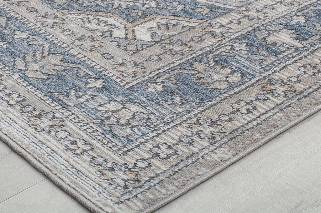 Close-up of the corner of an abstract rug with blue and beige patterns.