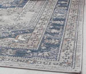 "Detailed view of the edge of an abstract blue and beige rug."