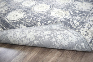 Close-up of an abstract rug folded over, showing the intricate gray and white pattern.