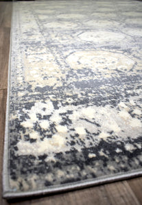 Close-up of the edge of an abstract rug with a geometric pattern in gray and white.