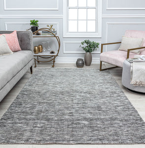 Gray area rug in a modern living room with gray sofa and white armchair.