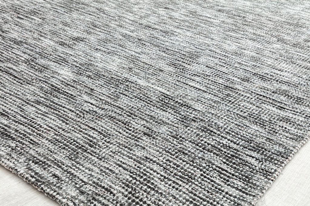 Detailed texture of a gray area rug on light flooring.