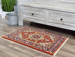 Small red and blue area rug with intricate patterns placed in front of a rustic cabinet.