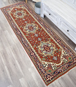 Red and blue runner rug with traditional designs placed in a rustic room.