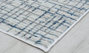 Close-up of the corner of a blue and gray geometric area rug, highlighting the intricate pattern and quality craftsmanship.