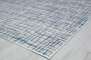 Corner view of a blue and gray geometric area rug on a light wood floor, showcasing its detailed pattern and modern design.