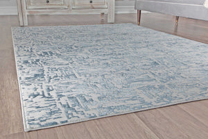 Close-up of a blue and white area rug on wooden flooring.