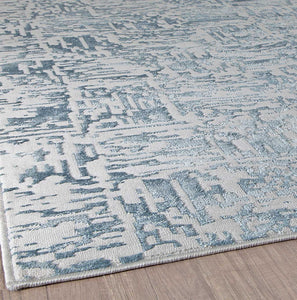 Abstract blue and white area rug in a modern living space with wooden flooring.