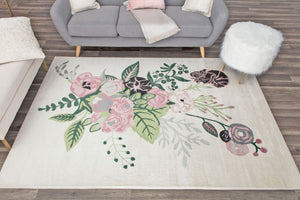 Floral rug in a living room setting, featuring green leaves and pink flowers on a cream background, complementing modern decor.