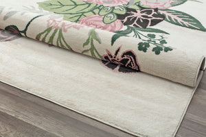 Floral rug rolled to display design with pink flowers and green leaves on a cream background, highlighting the rug's thickness and texture.