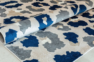 Close-up of a rolled blue and gray floral patterned rug highlighting its abstract flower designs.