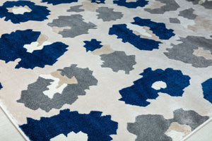 Close-up of the corner of a blue and gray floral patterned rug with abstract flower designs.