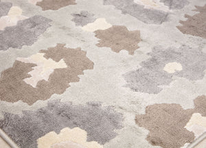 Close-up of the corner of a beige and gray floral patterned rug with abstract flower designs, showcasing its detailed texture."