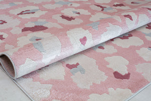 "Close-up of a rolled pink and beige floral patterned rug highlighting its abstract flower designs.