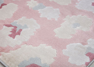 Close-up of a pink and beige floral patterned rug with abstract flower designs, showcasing its detailed texture.