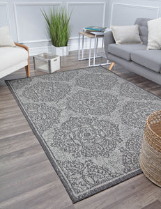 Minimalist living room with a gray and white patterned rug, modern furniture, a green plant, and a wicker basket accent.