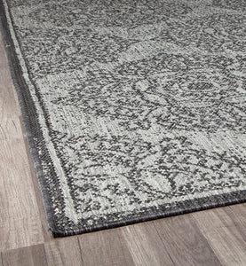 Edge view of a grey abstract area rug with detailed patterning.