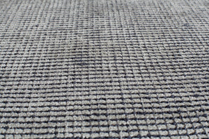 Close-up of a gray woven area rug, showcasing its detailed texture and craftsmanship.