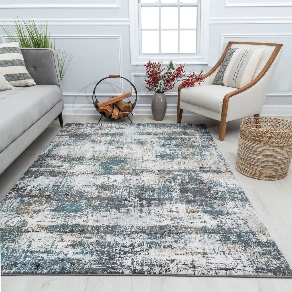 Cozy living room with a grey sofa, a white armchair, a rustic firewood holder, a blue and grey abstract rug, and decorative plants