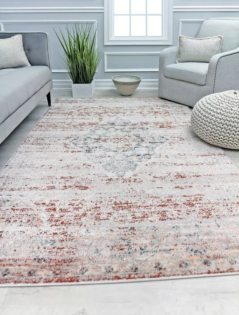 Vintage-style rug in a serene living room, with grey sofas, a potted plant, a cream pouf, and a decorative bowl on the floor