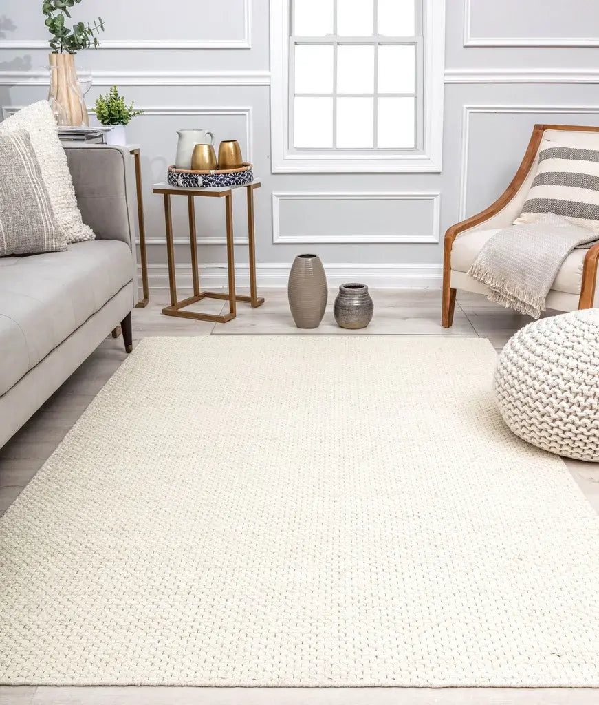 Cozy living room with a light gray sofa, neutral rug, wooden armchair, side table with decor, and decorative vases on the floor