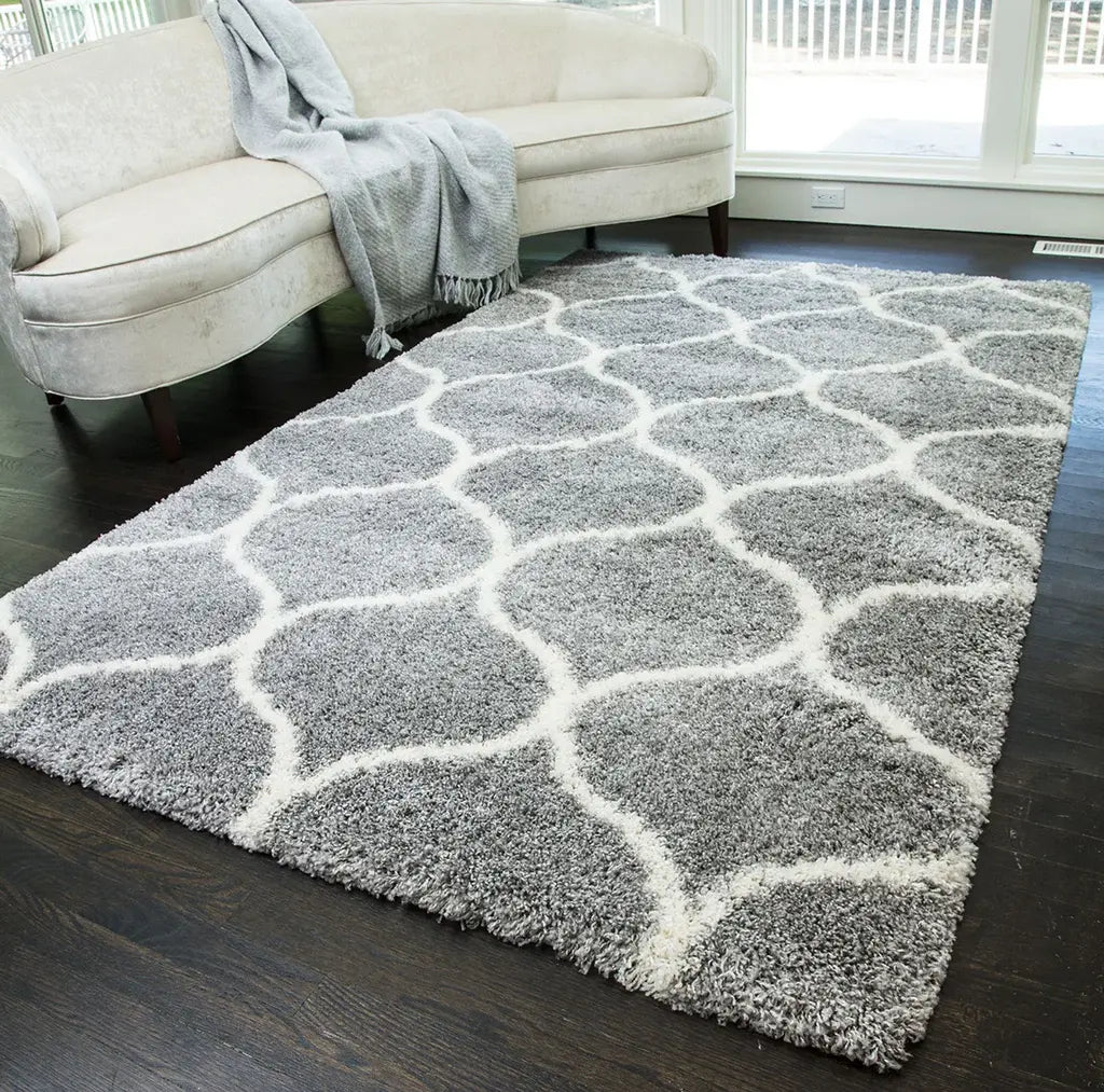 Elegant gray and white patterned rug in a cozy living room, featuring a cream sofa with a gray throw, and dark wood flooring