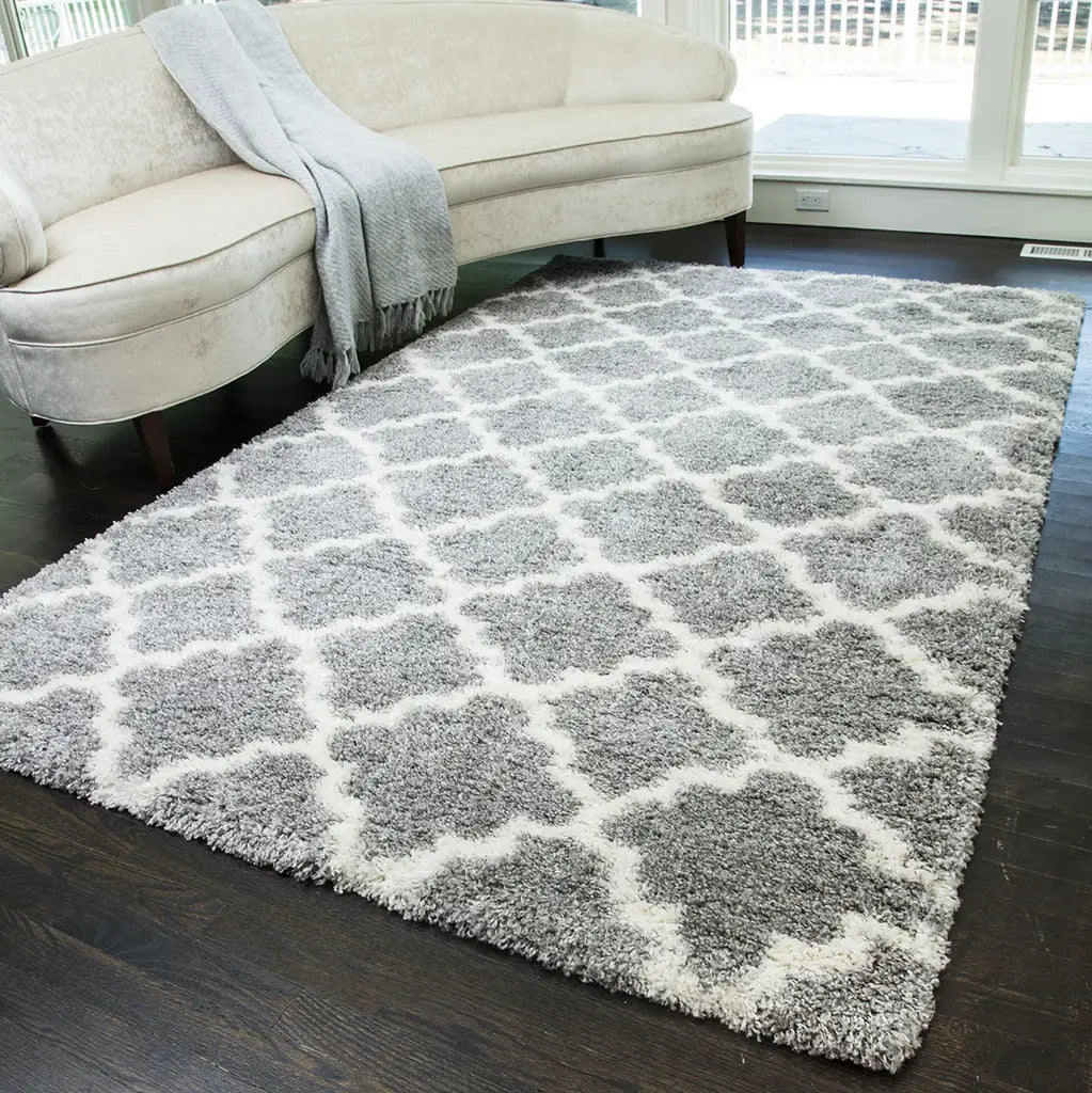 Chic gray and ivory quatrefoil patterned rug in a cozy living room, featuring a cream sofa with a gray throw, and dark wood flooring