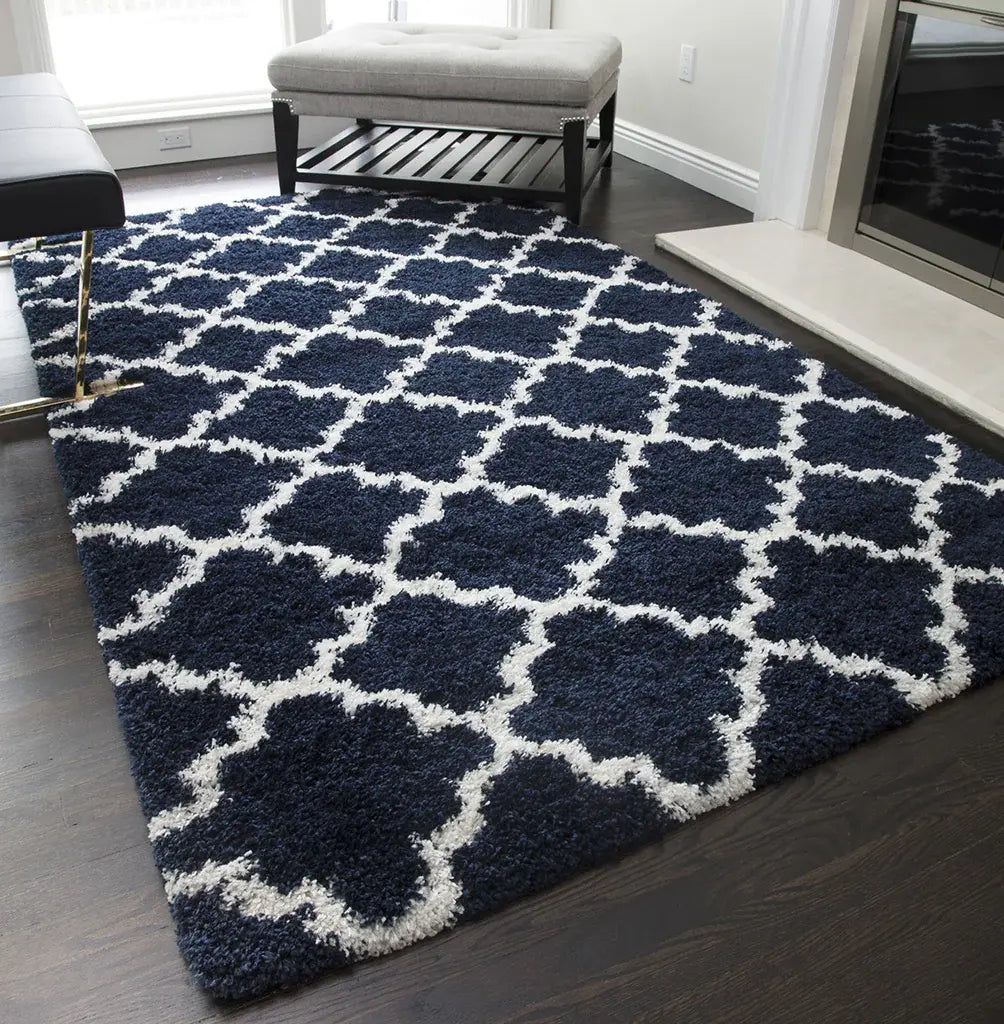 Chic navy and white quatrefoil patterned rug in a modern living room, complemented by a white bench and dark hardwood flooring.