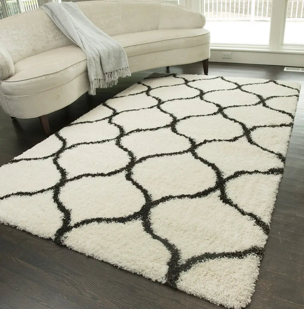 Stylish ivory and charcoal patterned rug in a contemporary living room, featuring a cream sofa with a gray throw, and dark wood flooring