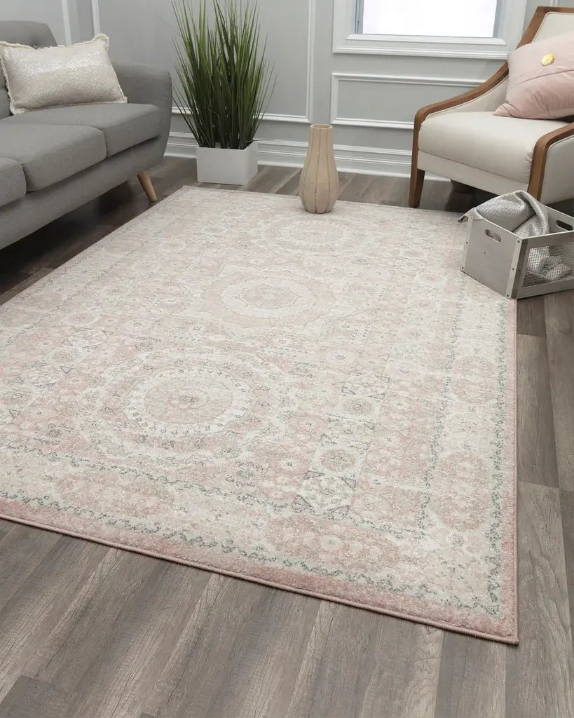 Living room with a white rug featuring a black scroll pattern, gray sofa, beige bench, green plant, and decorative vases on wooden floor.