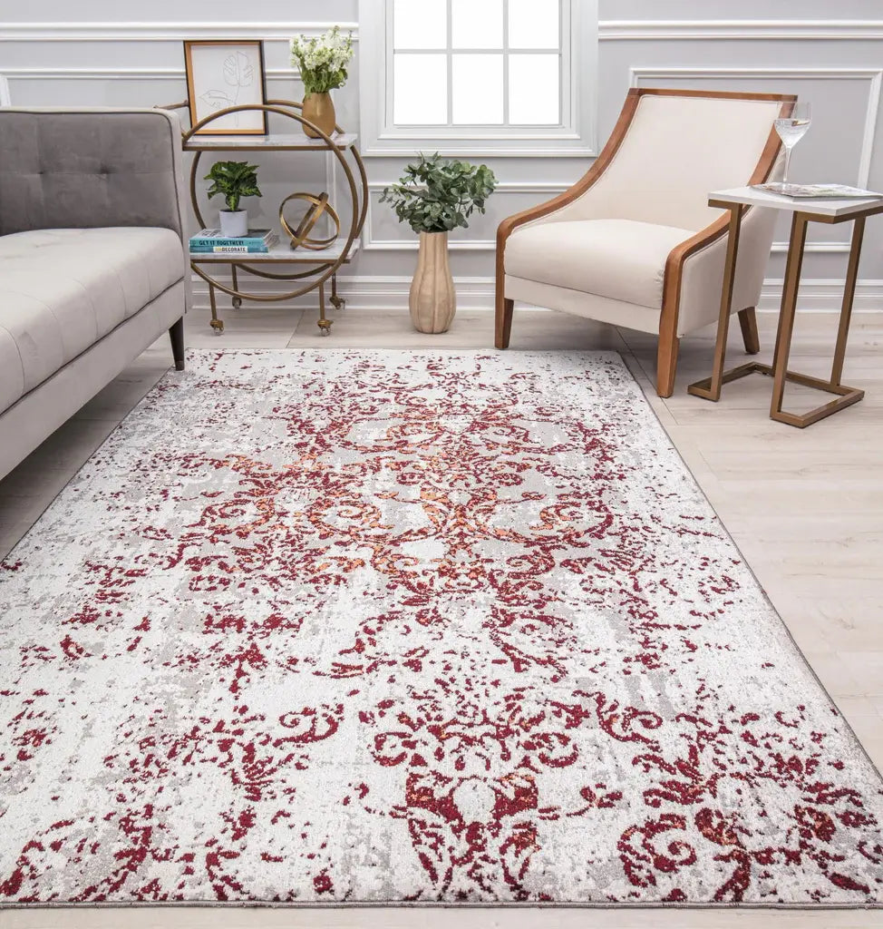 Chic living room with a grey sofa, a white armchair, a red and white patterned rug, decorative plants, and a round table.