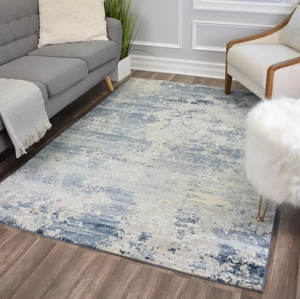 Soft blue and white rug with abstract patterns, placed in a minimalist living room with contemporary furniture.