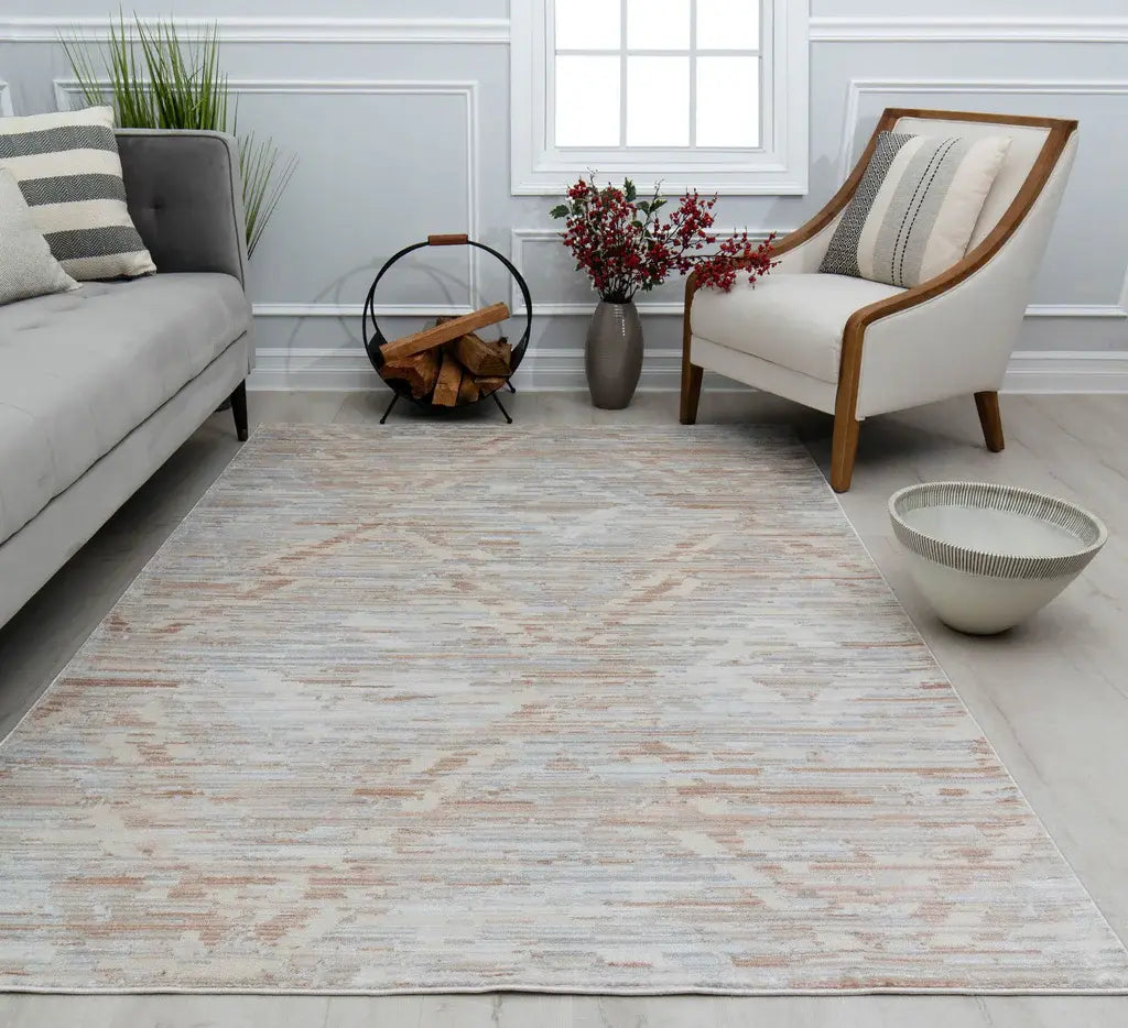 Minimalist living room with a grey sofa, a white armchair, a light beige abstract rug, a rustic firewood holder, and decorative plants.