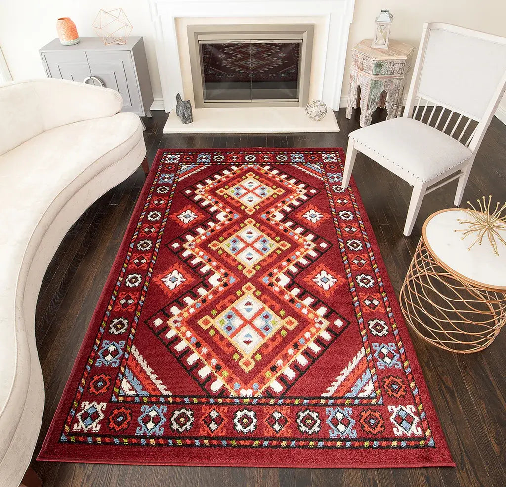 Bold red and orange geometric rug with traditional patterns, adding warmth to a stylish living room with dark flooring.