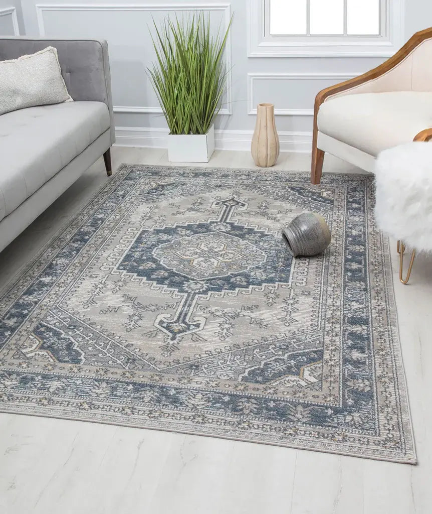 Classic living room with a blue and beige ornate patterned rug, gray sofa, white armchair, and green plant for a timeless look