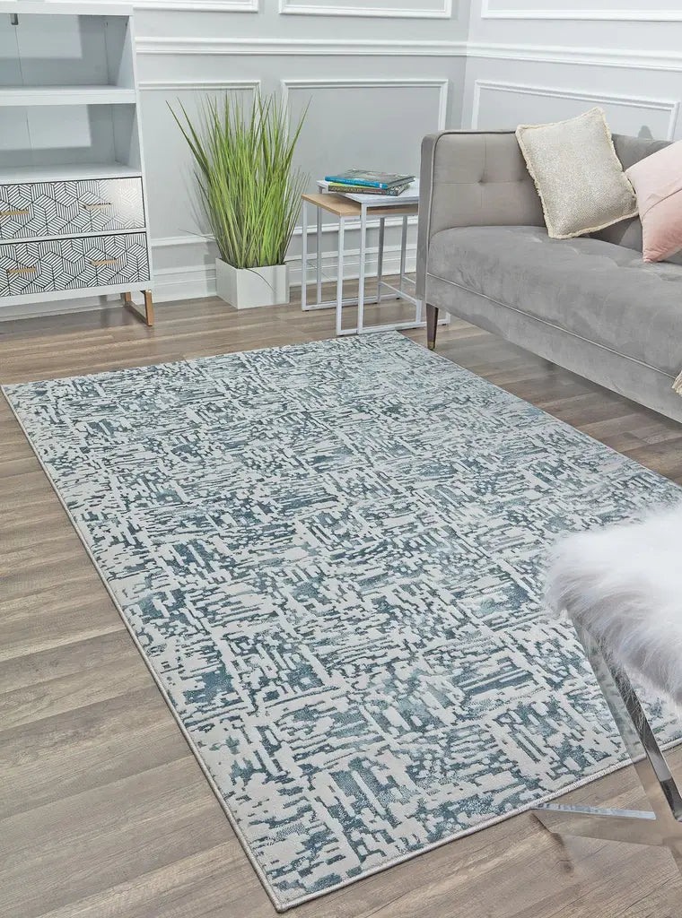 Contemporary blue and white area rug in a modern living room with gray sofa and green plant.